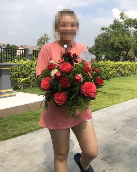 ลูกค้ากำลังรับกระเช้าดอกไม้ที่คล้ายกัน มีกุหลาบแดง คาร์เนชั่นแดง ดอกไม้สีครีม (สินค้าอื่น)