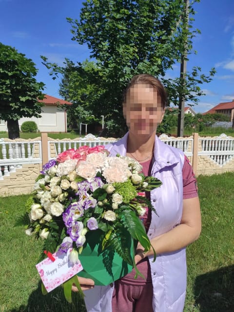 ลูกค้ากำลังรับกล่องดอกไม้ที่คล้ายกัน มีคาร์เนชั่นพีชและครีม กุหลาบชมพูและครีม ลิเซียนทัสม่วงและขาว ไฮเดรนเยียเขียว พร้อมการ์ด (สินค้าอื่น)
