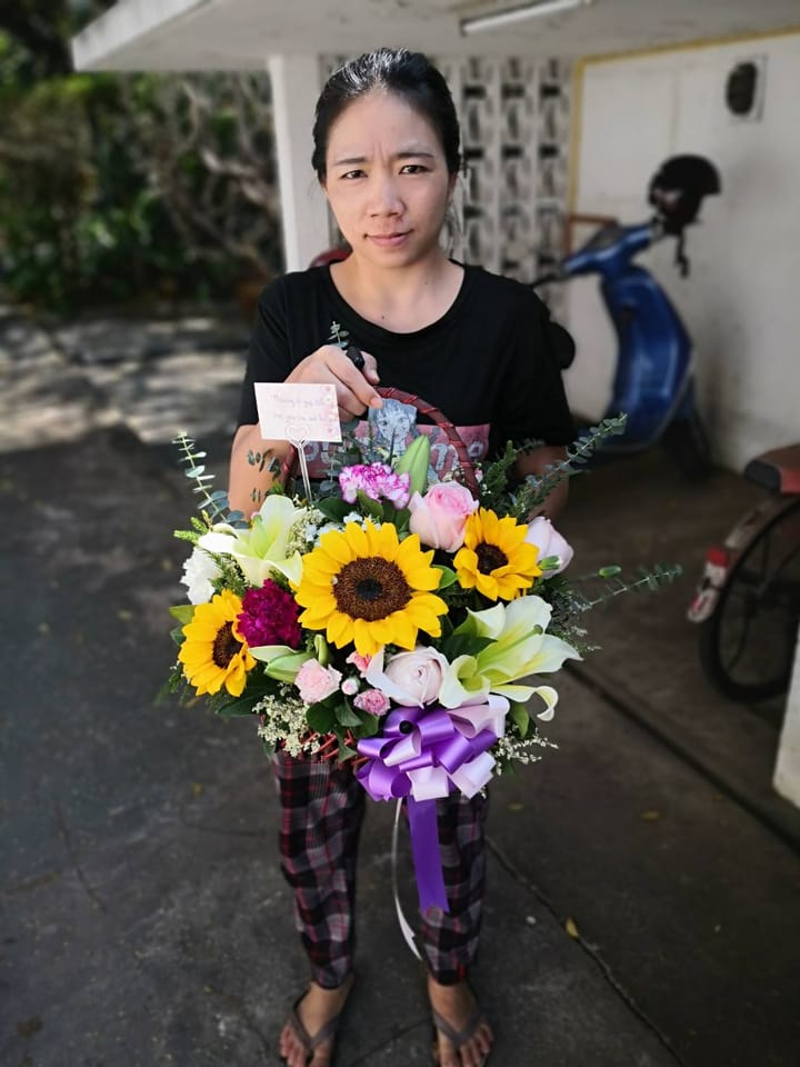 ลูกค้ากำลังรับช่อทานตะวัน ลิลลี่ คาร์เนชั่น และกุหลาบ สีเหลือง ขาว และชมพู (สินค้าอื่น)