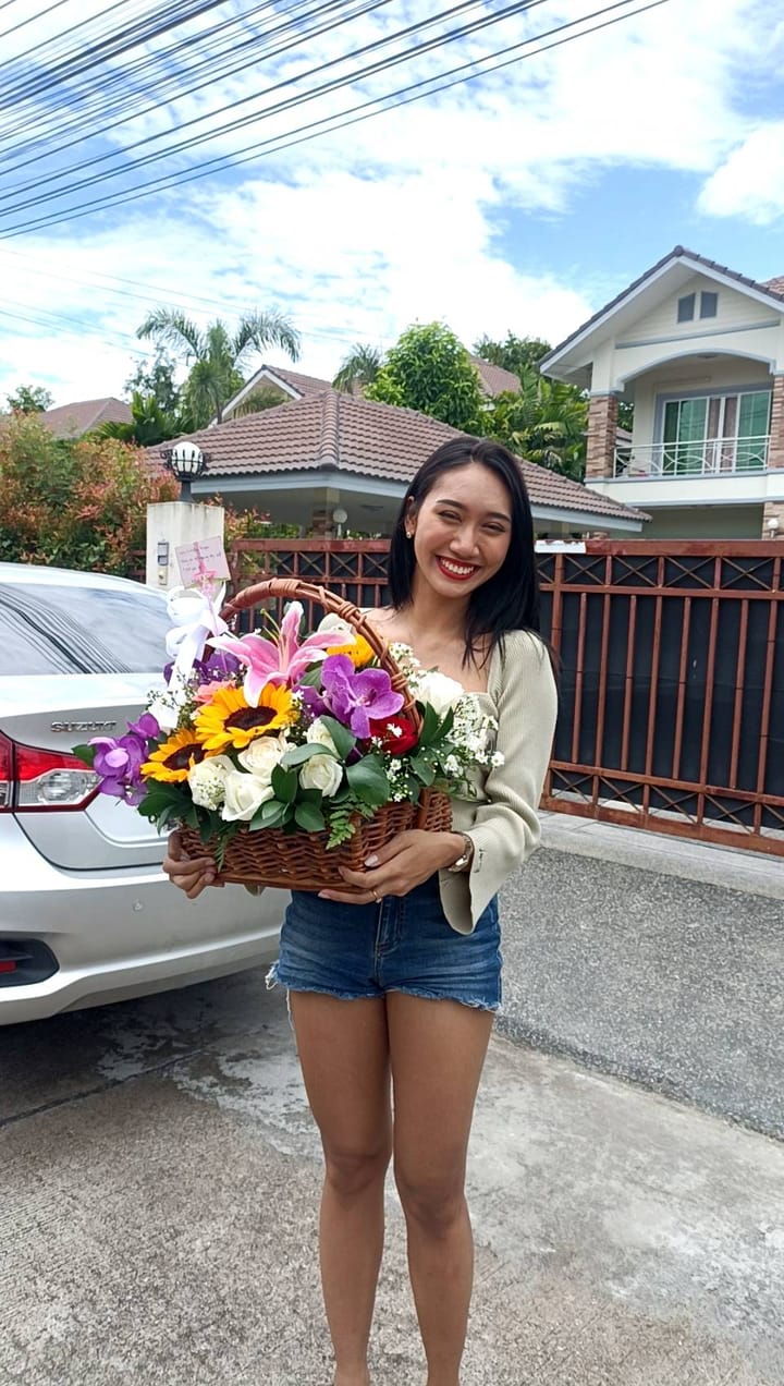ลูกค้ากำลังรับช่อลิลลี่ ทานตะวัน กุหลาบ และกล้วยไม้ สีชมพู เหลือง และขาว (สินค้าอื่น)