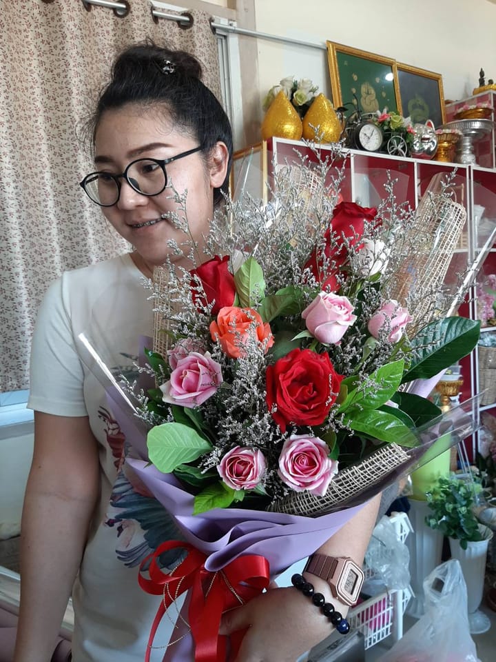 ลูกค้ากำลังรับช่อกุหลาบแดง ชมพู และส้ม (สินค้าอื่น)