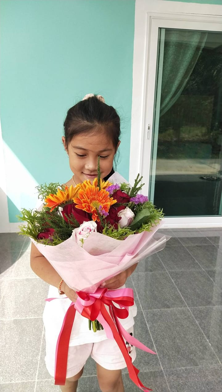 ลูกค้ากำลังรับช่อเยอบีร่า กุหลาบ และเบญจมาศ สีส้ม แดง และชมพู (สินค้าอื่น)
