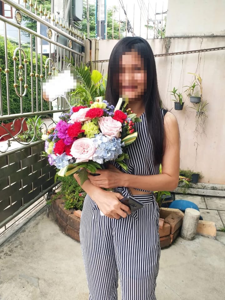 ลูกค้ากำลังรับช่อดอกไม้ที่คล้ายกัน มีกุหลาบชมพู คาร์เนชั่นแดงและม่วง ไฮเดรนเยียฟ้า คาร์เนชั่นเขียว (สินค้าอื่น)