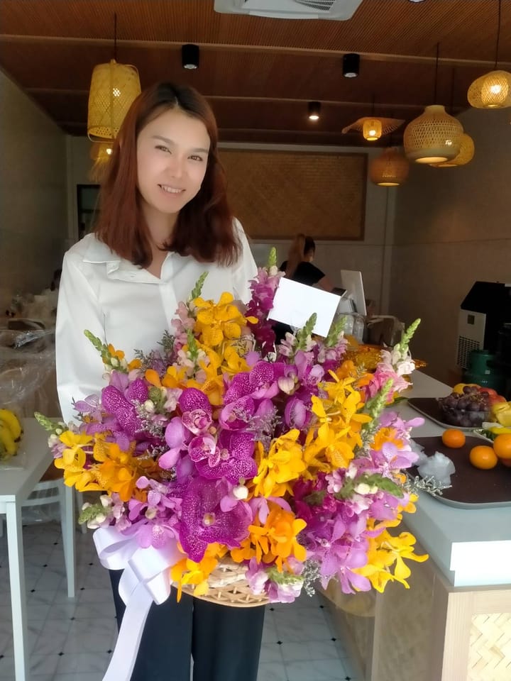 ลูกค้ากำลังรับช่อกล้วยไม้ม่วง เหลือง และชมพู (สินค้าอื่น)