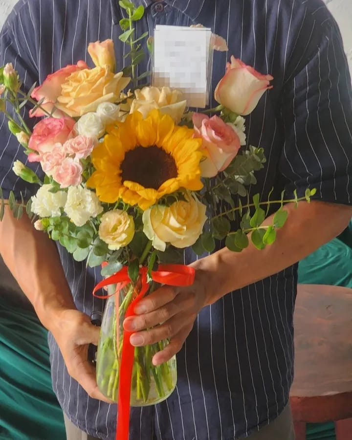 ลูกค้ากำลังรับแจกันดอกไม้ที่คล้ายกัน มีทานตะวันเหลือง กุหลาบพีชและเหลือง (สินค้าอื่น)