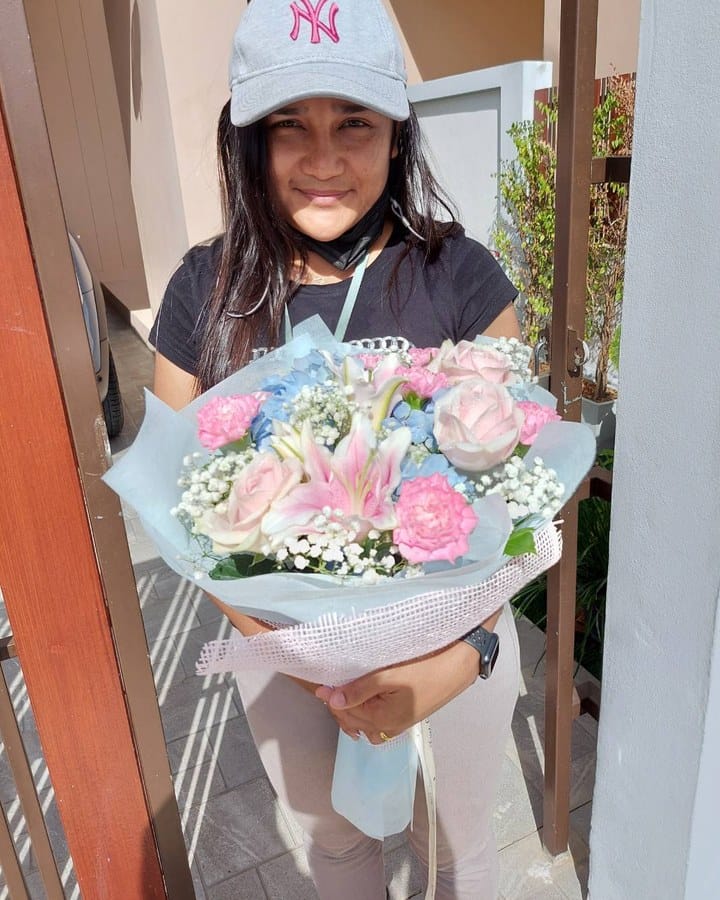 ลูกค้ากำลังรับช่อลิลลี่ กุหลาบ ไฮเดรนเยีย และยิปโซ สีชมพู ขาว และฟ้า (สินค้าอื่น)