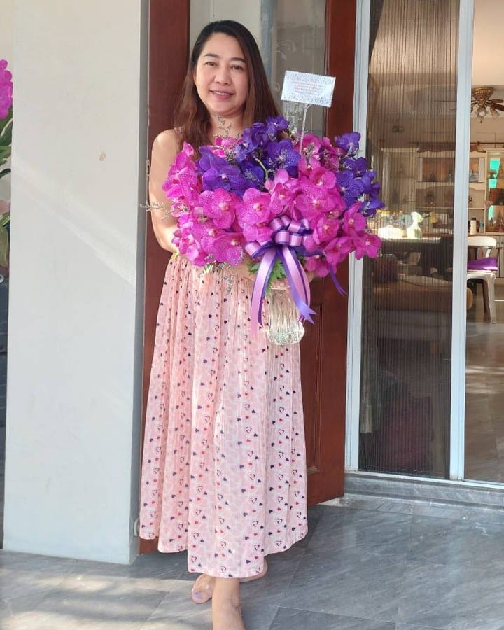 ลูกค้ากำลังรับช่อกล้วยไม้ชมพูและม่วง (สินค้าอื่น)